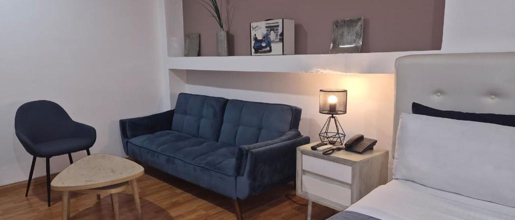 a living room with a blue couch and a bed at Hotel Zona G in Bogotá