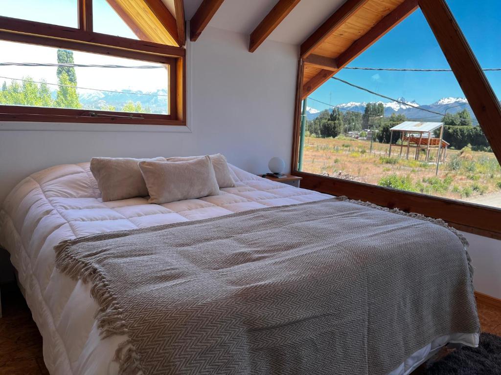 a bedroom with a bed and a large window at Cabañas Los Manzanos in Cholila