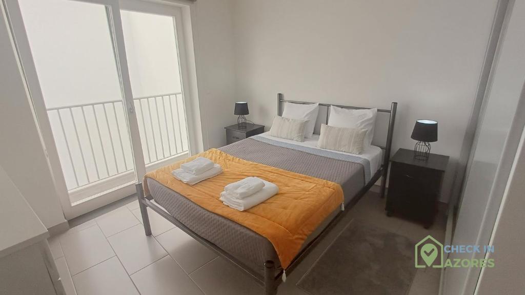 a bedroom with a bed with two towels on it at Terraço e vista deslumbrante no centro de Angra in Angra do Heroísmo