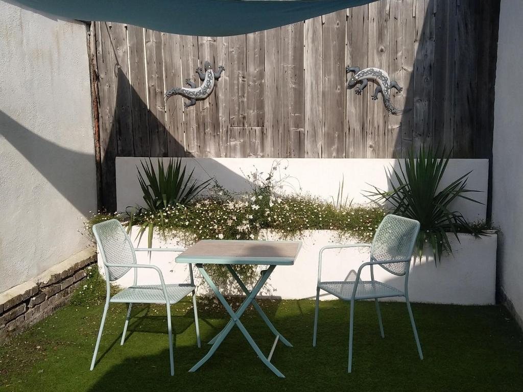 two chairs and a table in a yard with a fence at Gabrielle 40m2, Netflix in Sainte-Savine