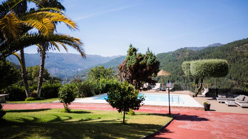 a pool with a palm tree and mountains in the background at Casa das Pedras in Vieira do Minho