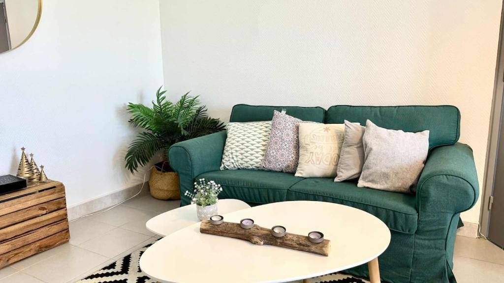 a living room with a green couch and a table at Tête en l'air- Cocon Lumineux- Centre Muret- Parking et commodités in Muret