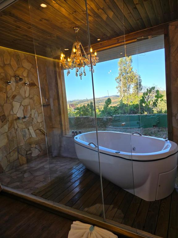 a bath tub in a room with a large window at Villa Dolce Amore - Boutique Hotel - Panorâmica in Campos do Jordão