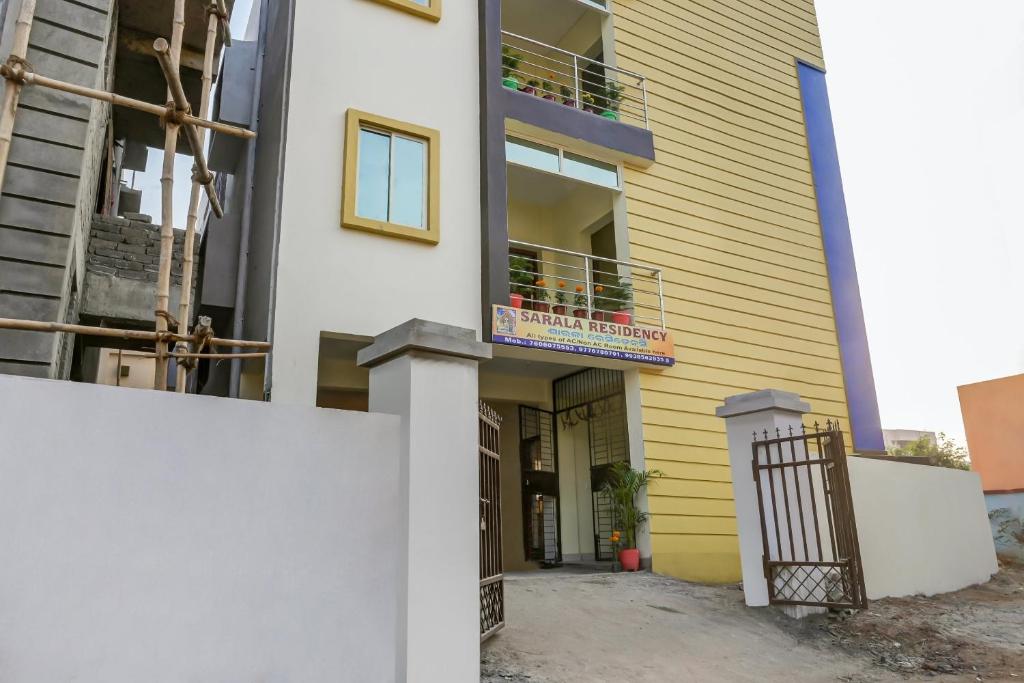 a yellow and white building with a balcony at Hotel O Sarala Residency in Bārang