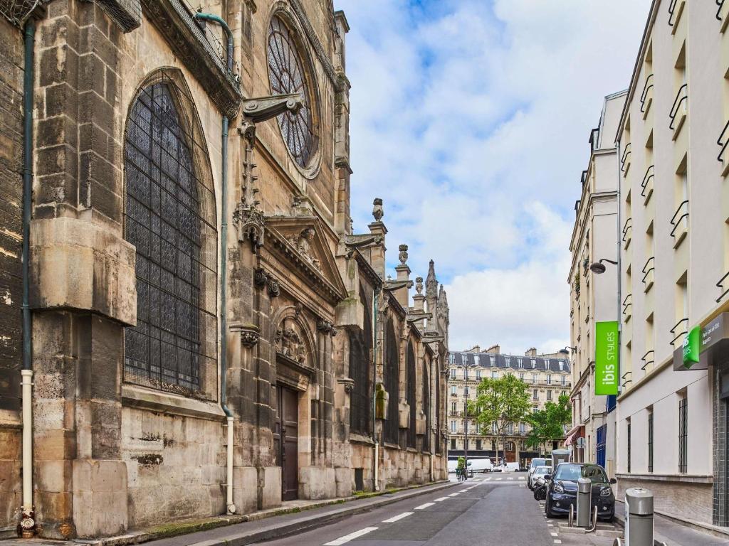 un viejo edificio con un reloj al lado de una calle en Ibis Styles Paris Gare de l'Est Magenta, en París