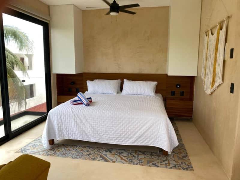 a bedroom with a white bed with a ceiling fan at A little slice of paradise in Puerto Morelos