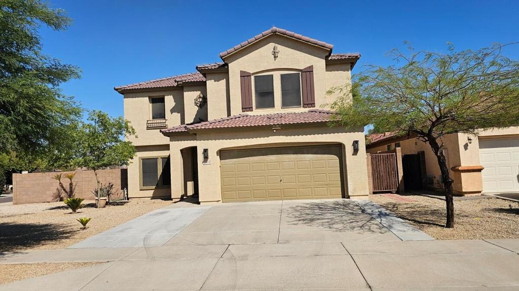 a large house with a garage and a driveway at Spacious 5-bedrm home 3 min from Cardinals Stadium in Phoenix