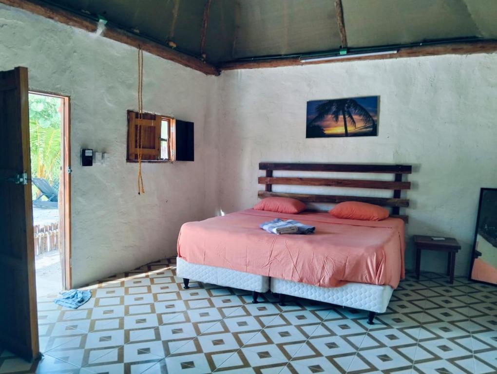 a bedroom with a bed with pink sheets and a window at cabañas Chulin Ha in San Benito