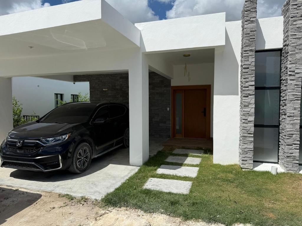 a black car parked in front of a white house at Modern House with Private Pool in Punta Cana in Punta Cana