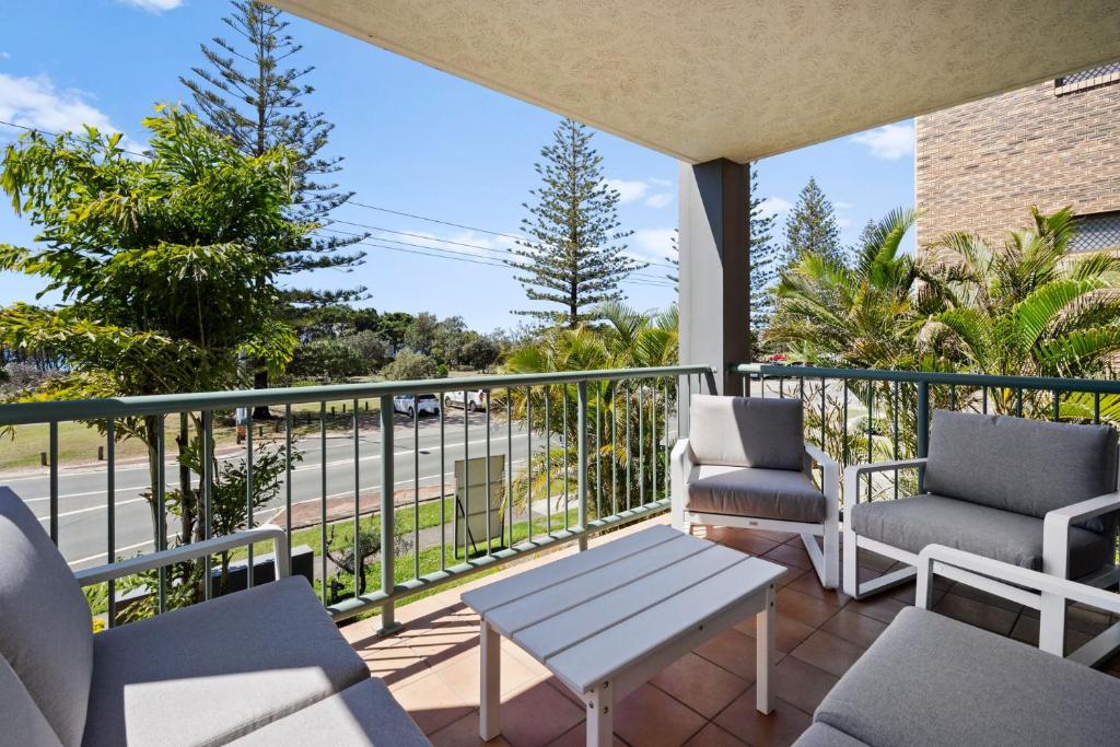 a balcony with chairs and a table and a view of a street at Kymberely - Beachfront Escape at Kingscliff in Chinderah