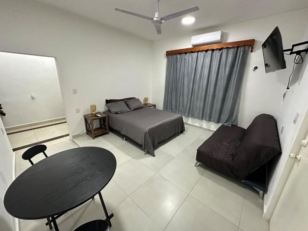 a bedroom with a bed and a table and a couch at AlcBalam Room in Bacalar