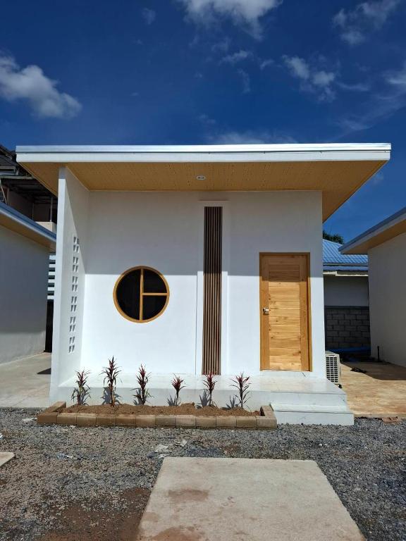 a small white house with a round window and a door at บีริช รีสอร์ท in Ban Pet