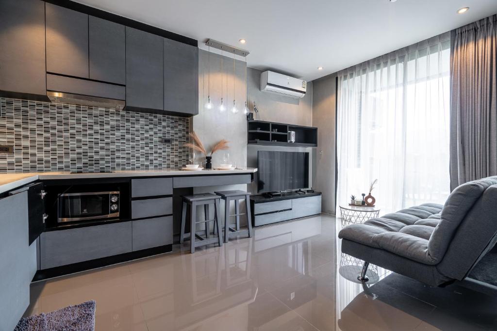 a kitchen with black cabinets and a couch and a chair at Luxury 1BR Apt Kamala Beach Resort P409 in Kamala Beach
