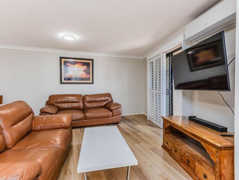 a living room with a leather couch and a flat screen tv at Tweed Coast Haven in Tweed Heads