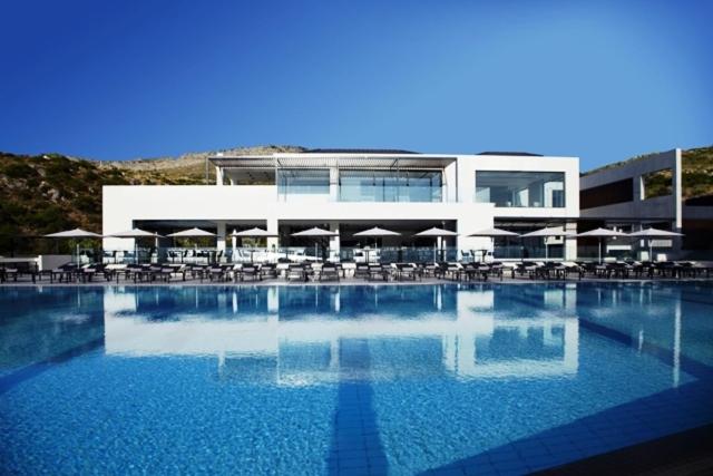 een groot zwembad met stoelen en een gebouw bij Tesoro Blu Hotel & Spa Adults Only in Skála Kefalonias