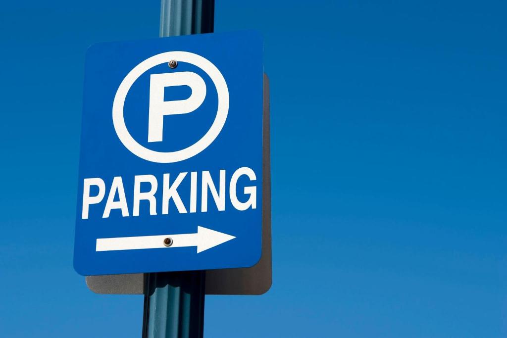 a parking sign with an arrow on a pole at Taribans Haven in Kalimoni