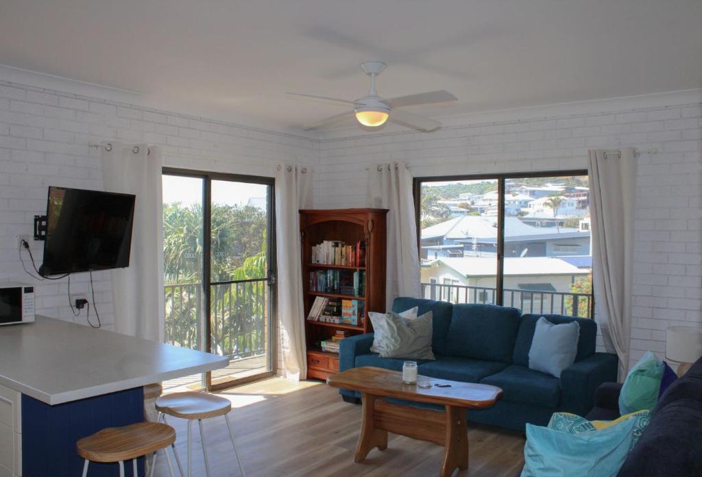 a living room with a blue couch and a table at Doc's Place at Crescent Head in Crescent Head