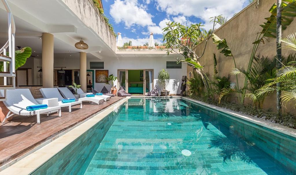 a swimming pool in a backyard with chairs and a house at Villa Josefine, 5 Bedroom pool, rooftop, pool table in Seminyak