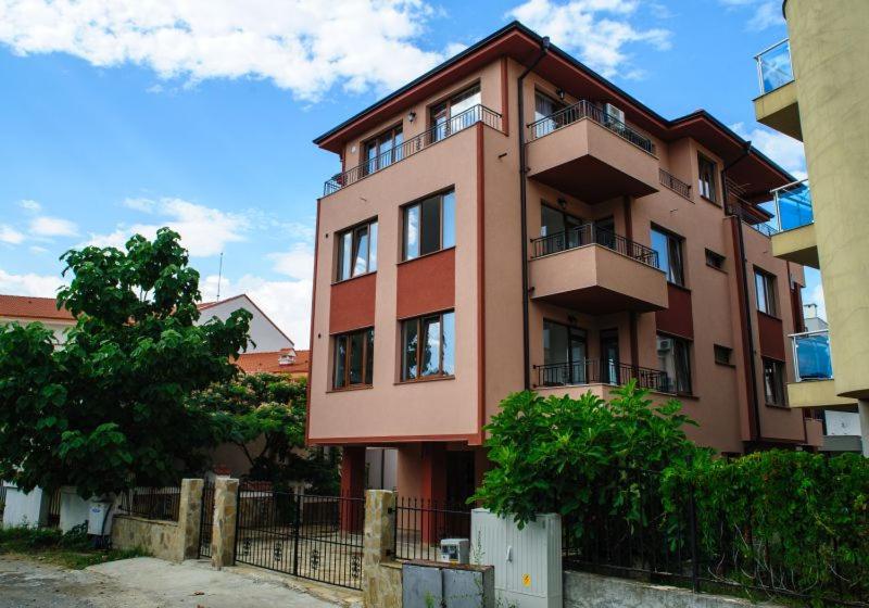 a tall pink building with a fence in front of it at Villa Maria in Tsarevo