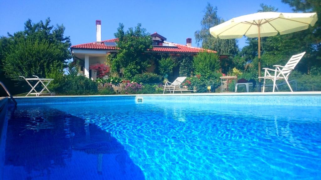 a swimming pool with two chairs and an umbrella at Ciliegissima in Pecetto