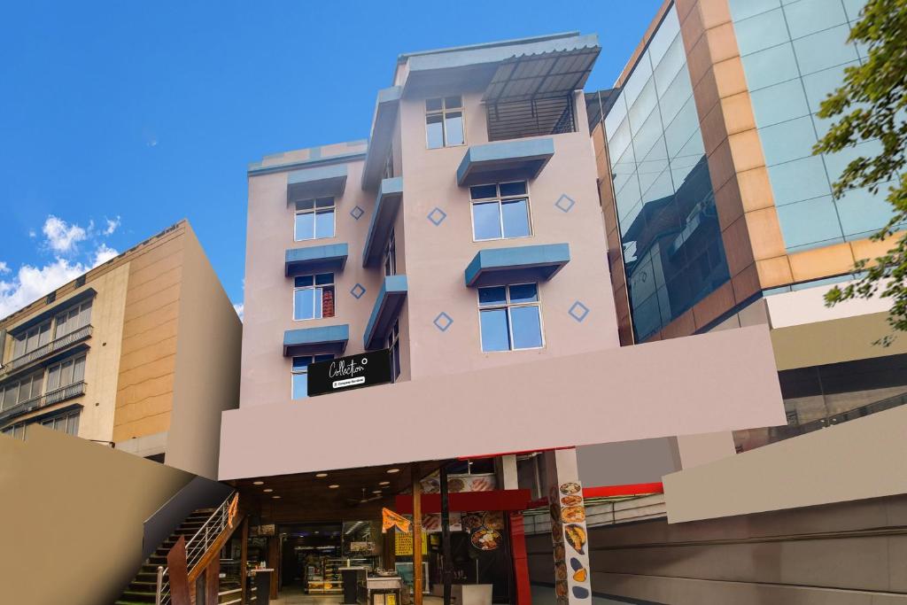 een roze gebouw met blauwe balkons aan een straat bij Super COLLECTION O SIXMILE GUWAHATI FORMERLY HOTEL GANGOTRI in Guwahati