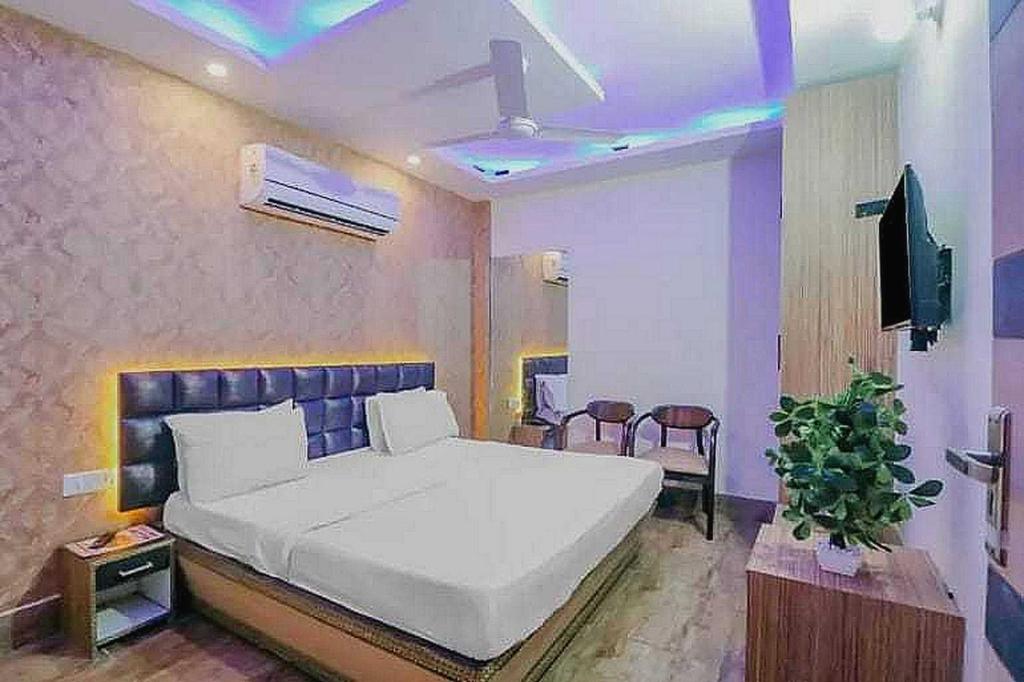 a bedroom with a large white bed and a tv at Super Hotel O Vivaan Residency in Rohtak