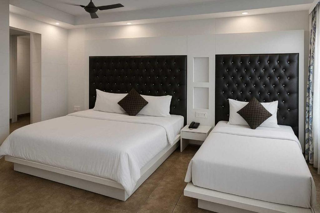 a bedroom with two beds with white sheets and a black headboard at Super Hotel O Vivaan Residency in Rohtak