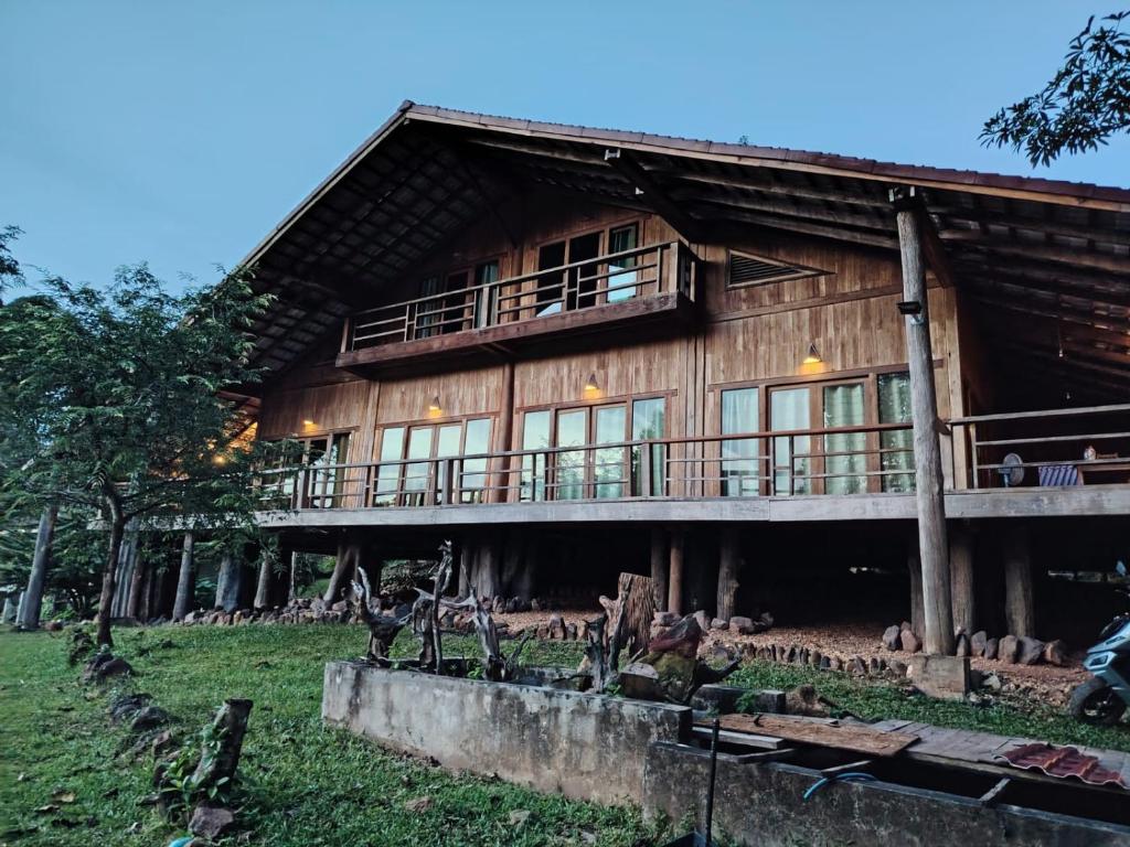 une grande maison en bois avec un porche et un balcon dans l'établissement Nirvana Archipel Resort, à Vang Vieng