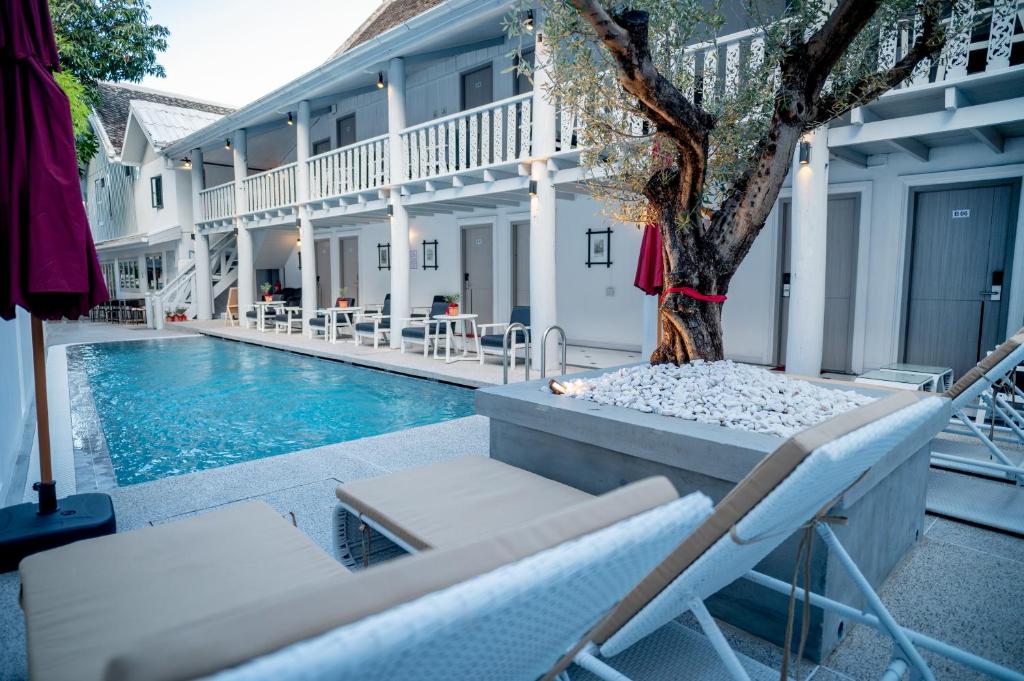 a pool with chairs and a tree next to a house at DownTown Hotel in Luang Prabang