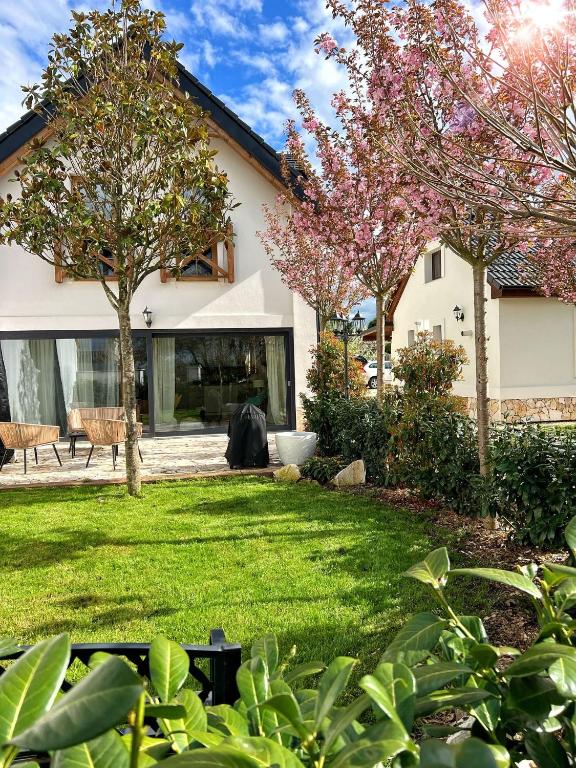a yard with flowering trees and a house at Deer Apartment in Lipí