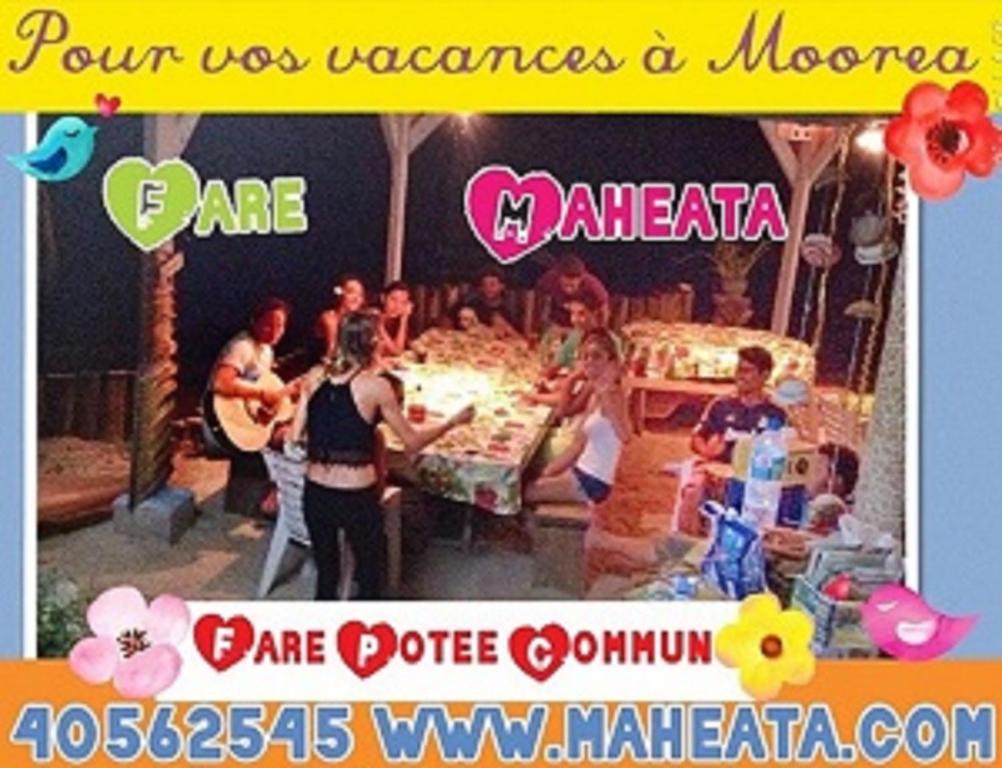a group of people standing around a table at a party at Fare Maheata in Pihaena
