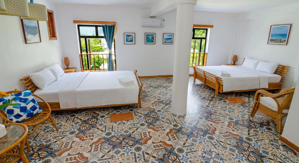 a bedroom with two beds and a table and chairs at Hotel De Condor in Con Dao