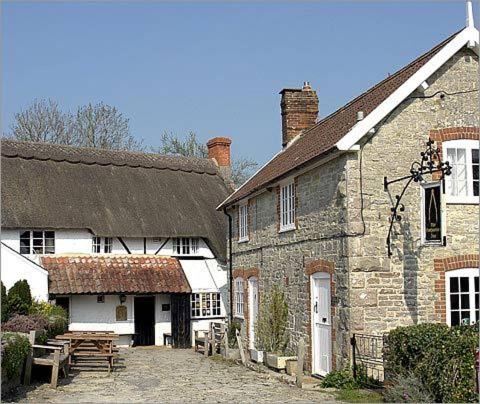 een oud bakstenen gebouw met een bank ervoor bij Compasses Inn in Tisbury