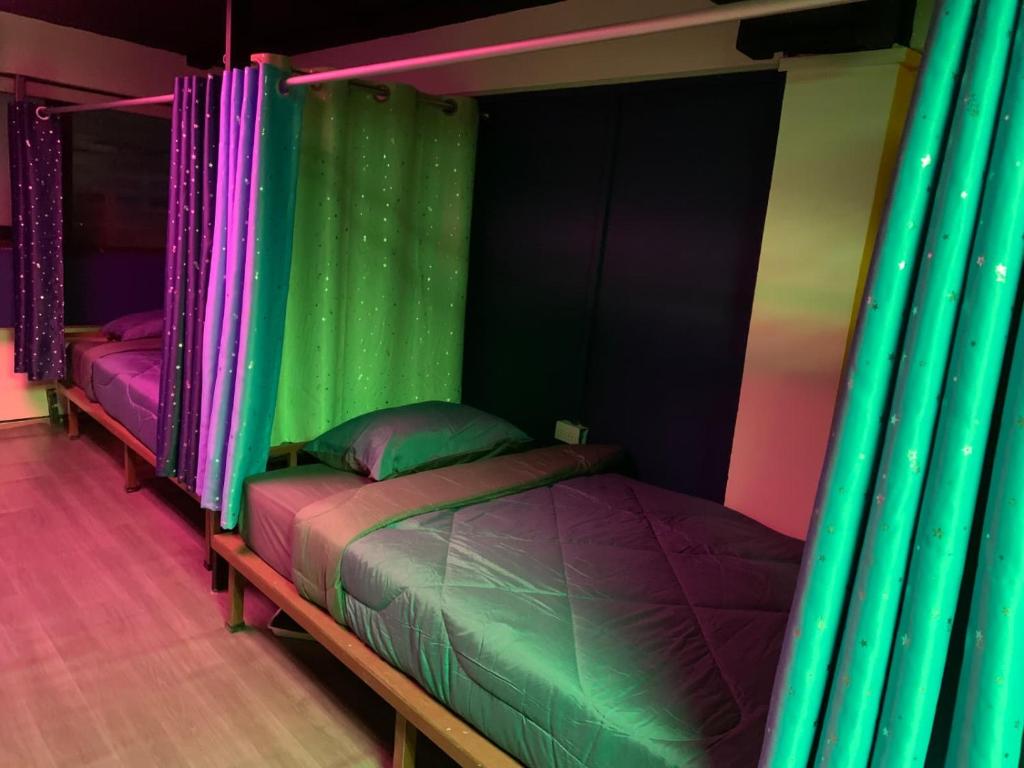 a bedroom with a bed with green and pink curtains at Roxx Social Hostel, Cafe & Bistro in Bangkok