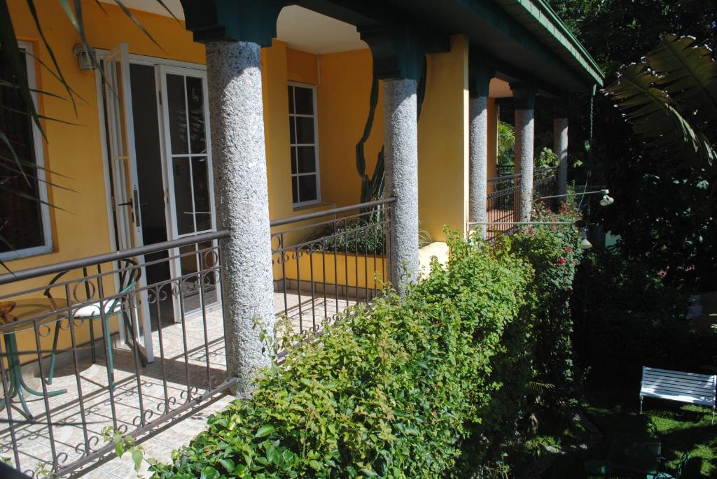 ein gelbes Haus mit Säulen auf einer Veranda in der Unterkunft Apart Hotel Valle Verde PLANES DE RENDEROS in San Salvador