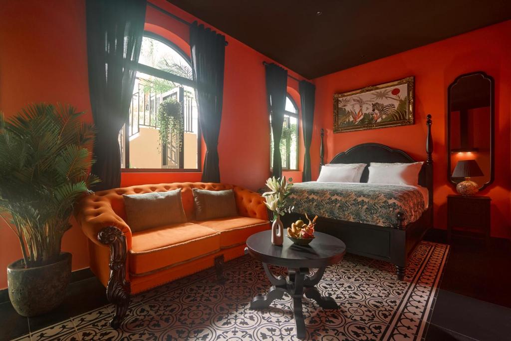 a bedroom with orange walls and a bed and a couch at G'Villa Thảo Điền in Ho Chi Minh City