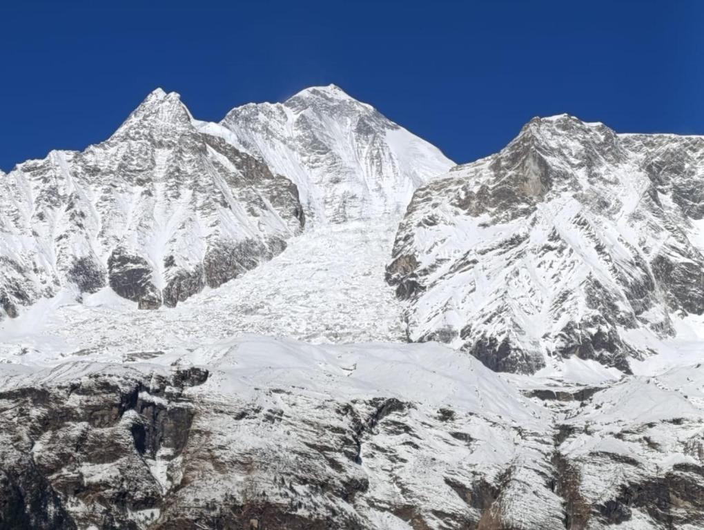 a group of snowy mountains with a blue sky at Hotel Srijana & Thakali Kitchen in Lete
