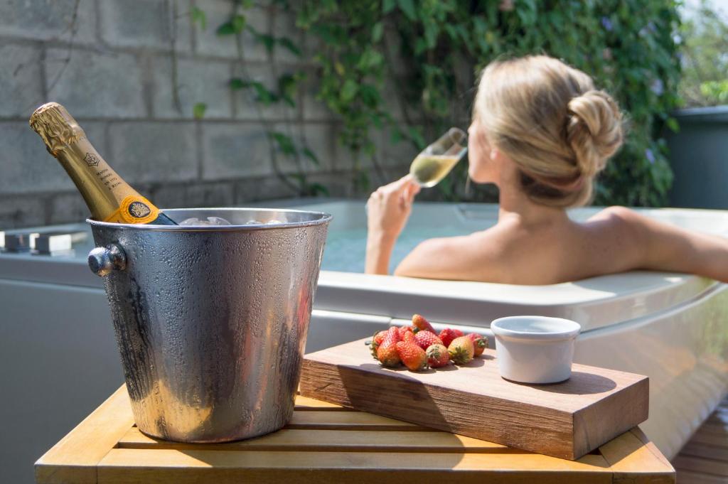a woman in a bath tub with a bottle of champagne and a plate of fruit at AcquaSanta Lofts Hotel in Cali
