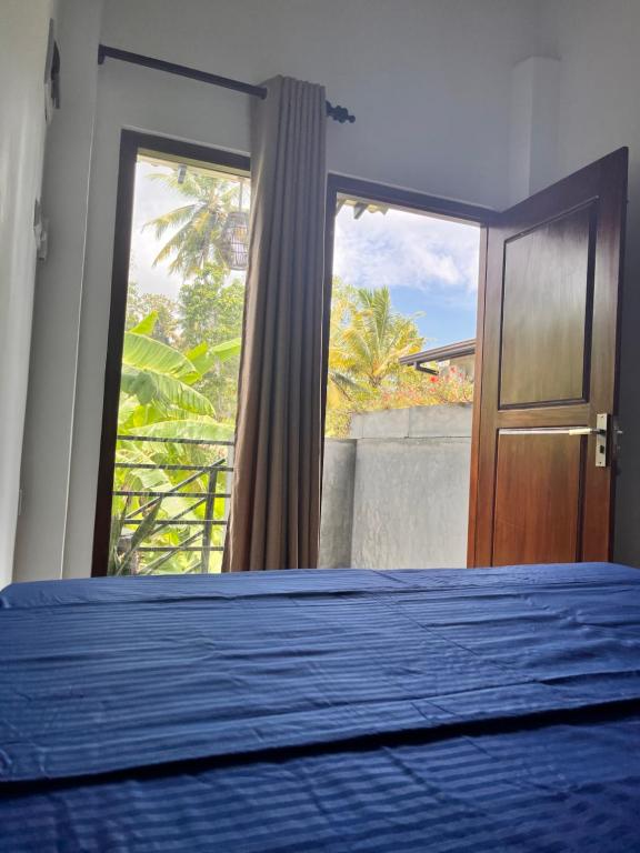 a bedroom with a blue bed and a window at Melon Guest - Weligama in Weligama
