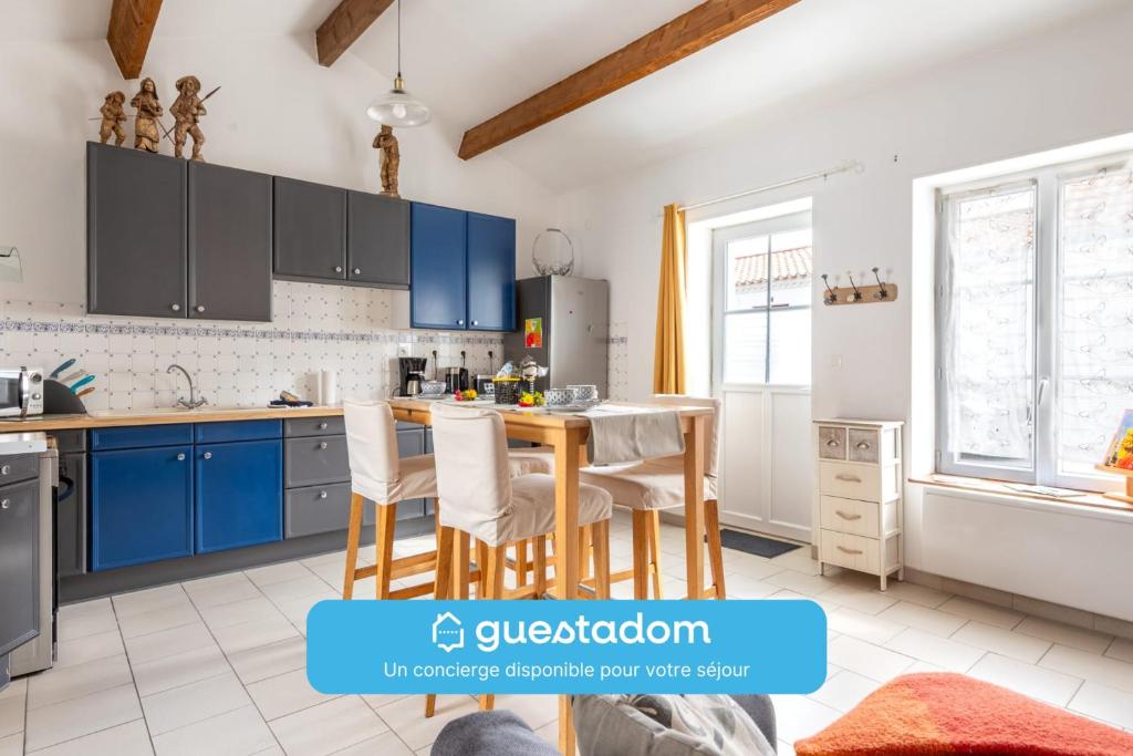 Una cocina con gabinetes azules y una mesa con sillas. en Entre Terre et Sel - Centre Bouin - Wifi, en Bouin