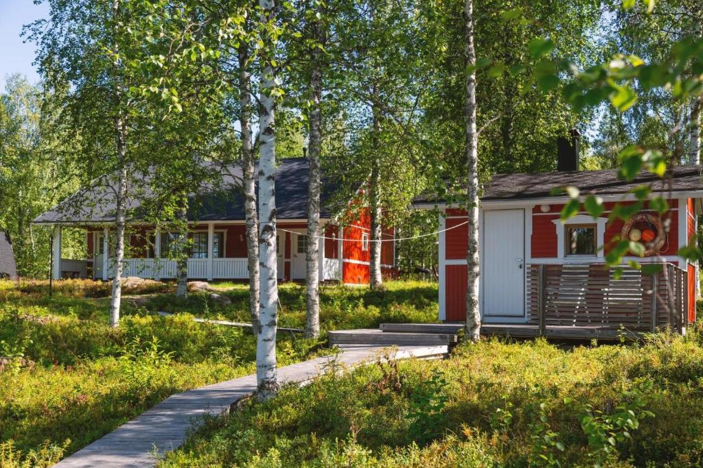 una pequeña casa roja y blanca en el bosque en Northern Lights Lakehouse, en Rovaniemi