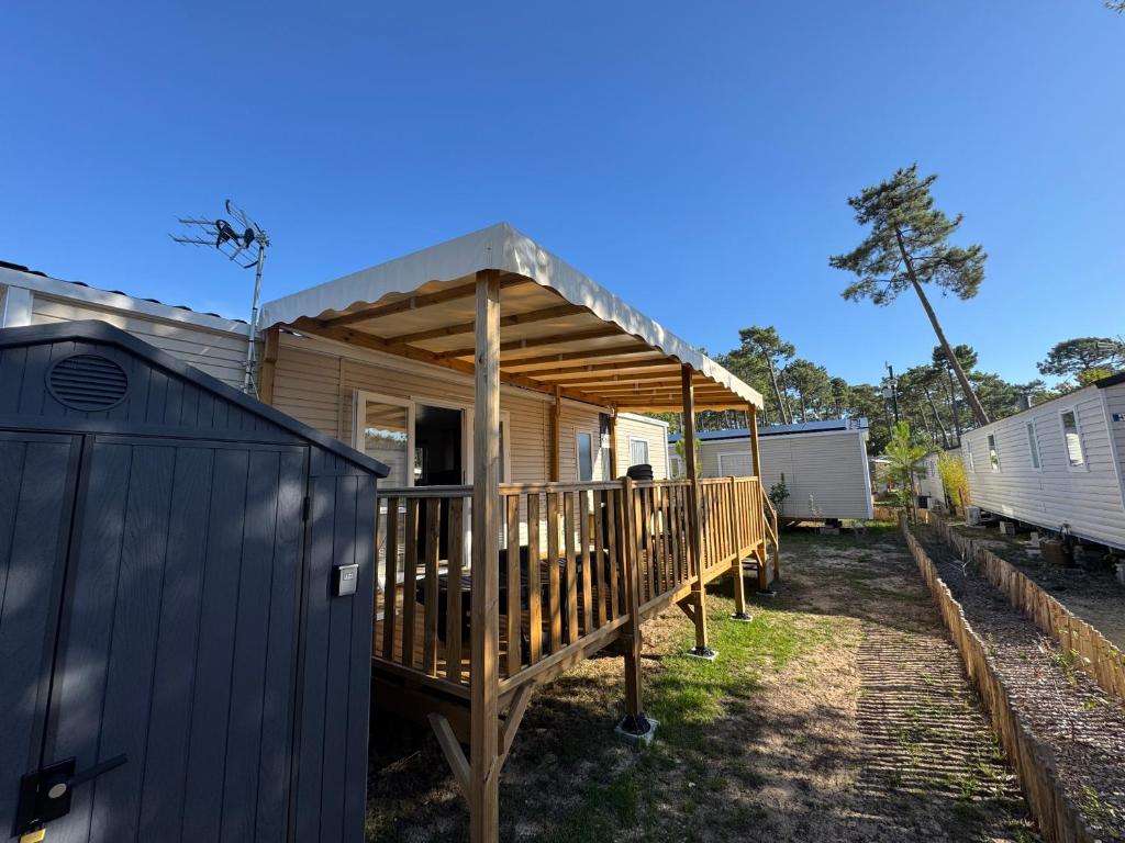 Casa con terraza de madera con techo en Mobil-home Bora camping les Embruns, en Lège-Cap-Ferret