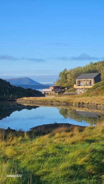 a house sitting on a hill next to a body of water at Sjåen på Balsnes Gård in Hitra