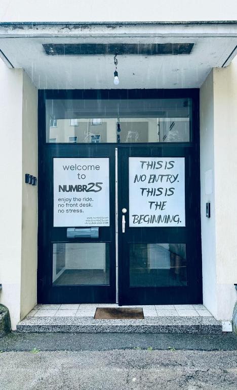 two signs on the front doors of a building at NUMBR25 - self service & low budget Hotel in Graz
