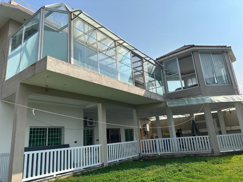 une maison avec un balcon en verre au-dessus dans l'établissement luxury villa in murree for families and couples, à Murree