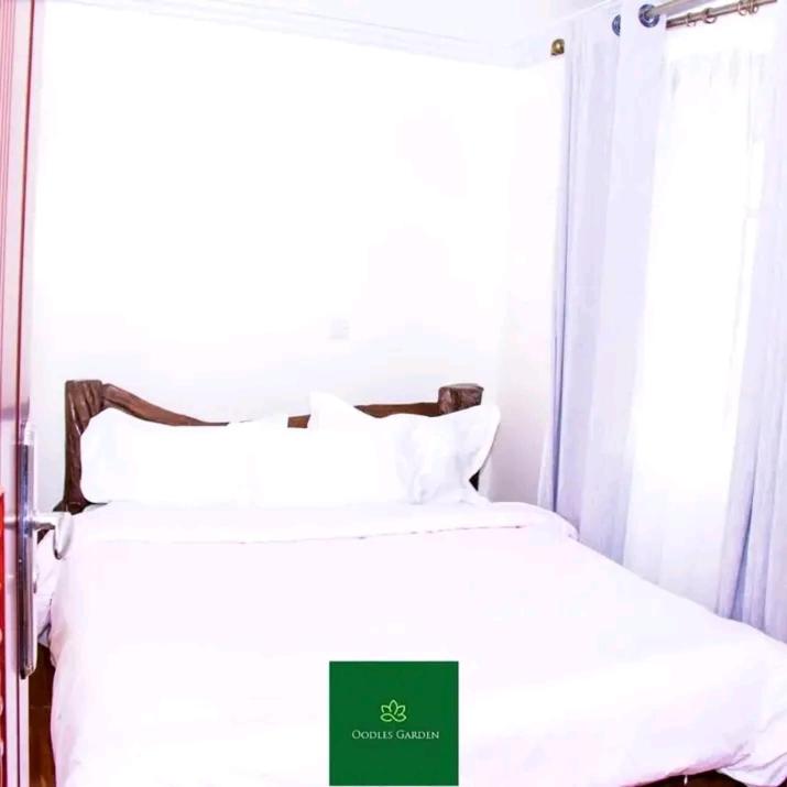 a bedroom with a bed with white sheets and a window at Oodles garden in Nairobi