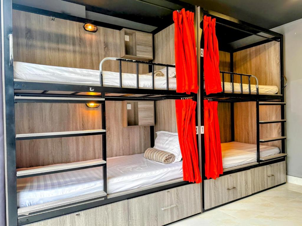 a room with three bunk beds with red curtains at Base Backpackers in Ho Chi Minh City