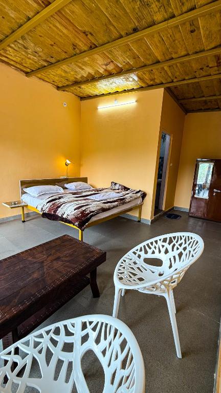 a room with a bed and a table and chairs at Datta's Heritage in Chaubattia