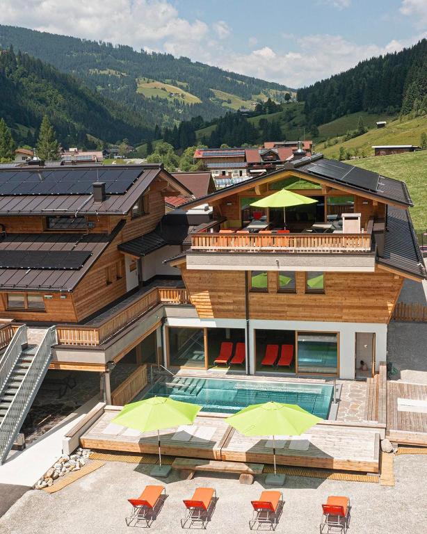 a house with a pool and some chairs and umbrellas at Alpin Chalet Kleinarl in Kleinarl