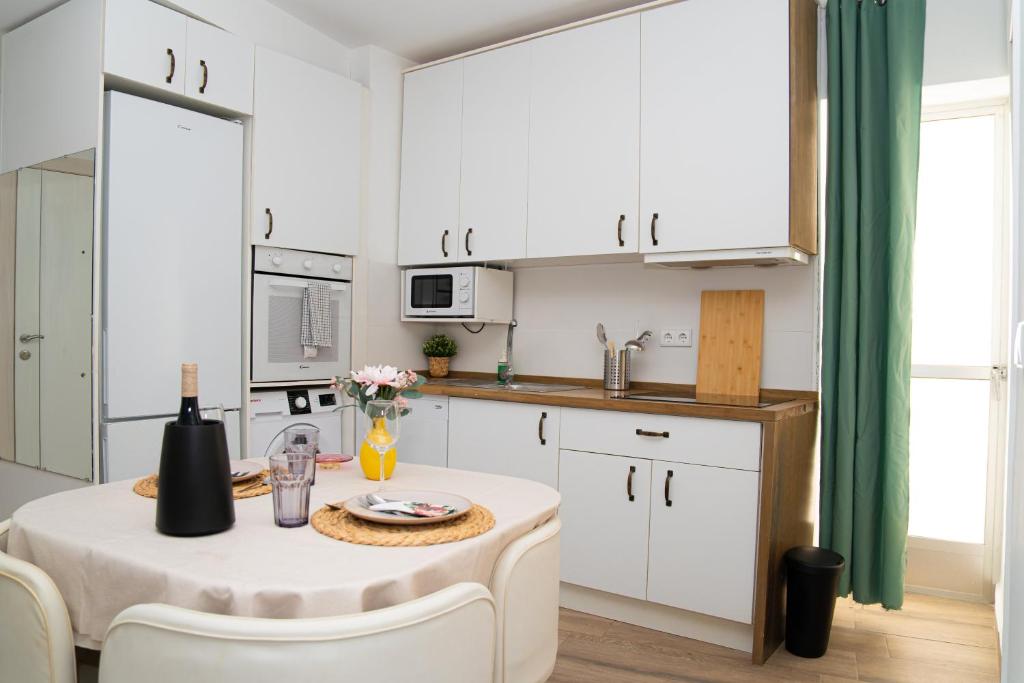 a kitchen with white cabinets and a table and chairs at Piso Acogedor a Metros de la Plaza de las Flores in Murcia